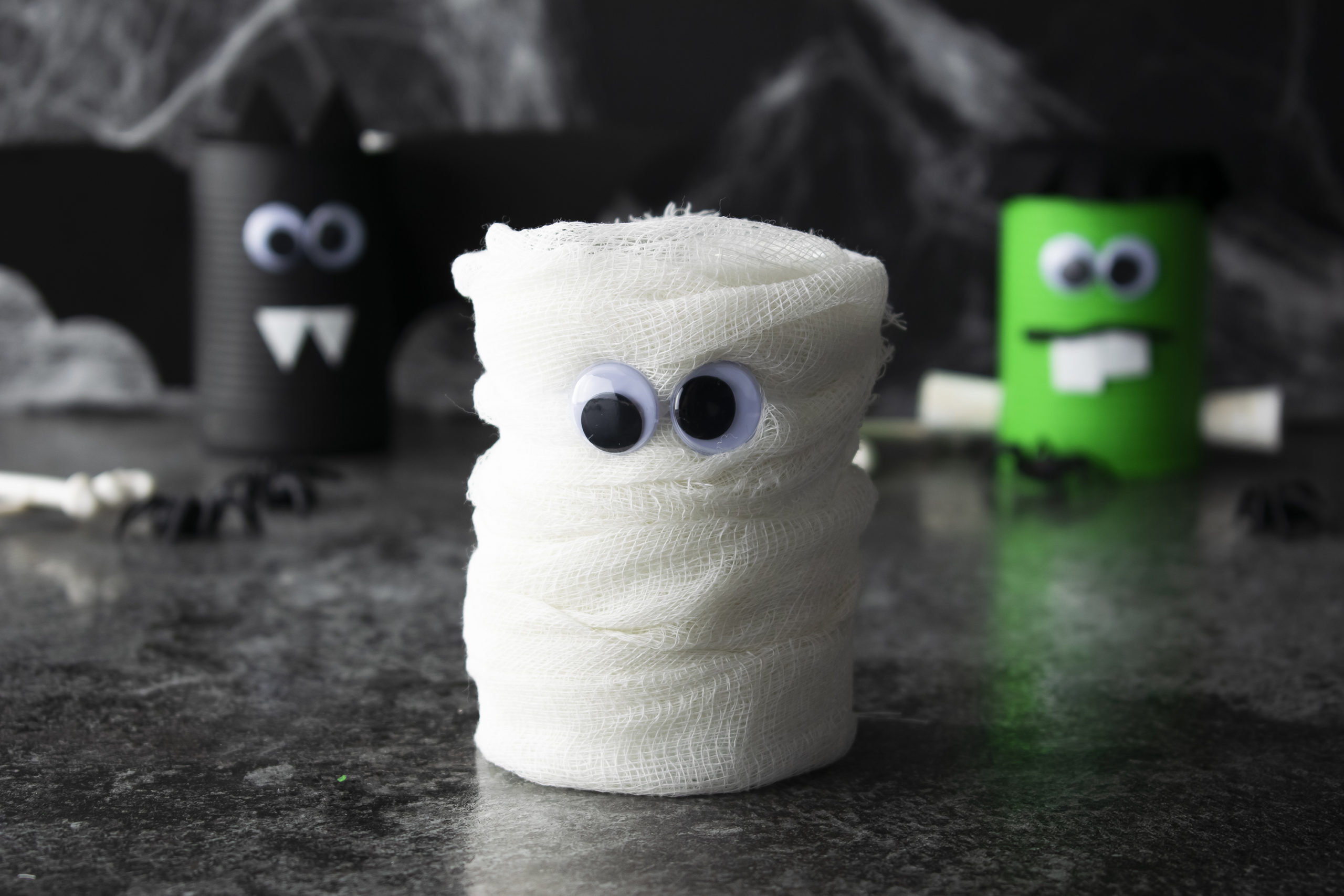 Easy-to-make “spooky cans” resembling a bat, Frankenstein and a mummy. Fun Halloween party activities for kids on mybergen.com.